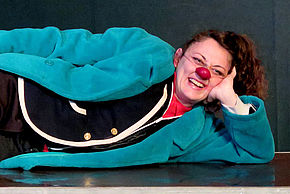Photo de l'artiste Elena Adragna, allongée au sol avec un nez de clown - Agrandir l'image