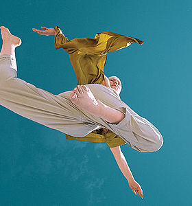 Photo d'une danseuse dans les airs sur fond bleu turquoise