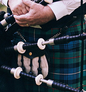 Photo d'une cornemuse dans les mains d'un musicien portant un kilt