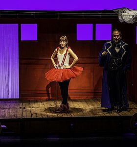 Photo de la pièce "L'école des femmes de Molière" représentant une femme en tutu de danse rouge et un homme à sa gauche en manteau bleuà Dammarie-lès-Lys