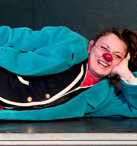 Photo de l'artiste Elena Adragna, allongée au sol avec un nez de clown