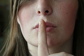 Photo d'une personne mettant son index devant la bouche (symbole du silence)