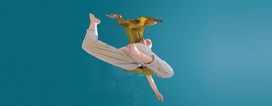 Photo d'une danseuse faisant une pose de danse dans les airs, sur fond de ciel bleu turquoise